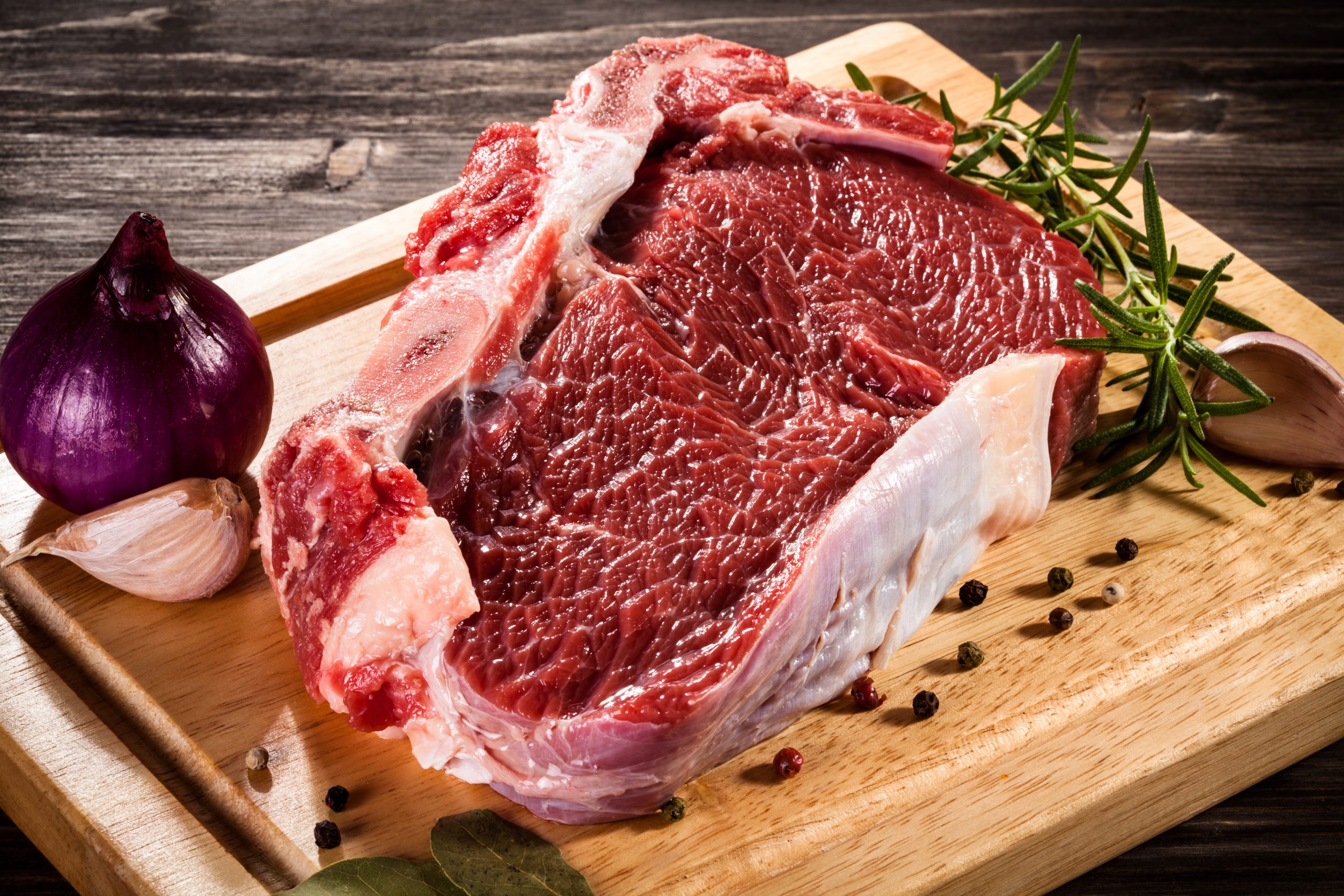 Raw beef on cutting board and vegetables